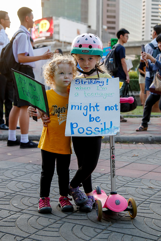 一对环保姐妹花周五在曼谷街头出席示威活动，举牌呼吁人们正视气候问题。（欧新社）
