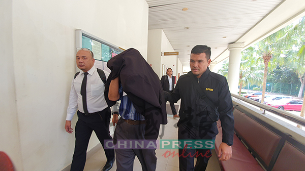 被告沙希淡（左2），在依斯占和反贪局官员的陪同下，步出法庭。