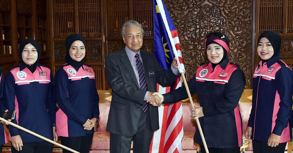 马哈迪（中）移交国旗给我国女探险家莎丽花（右2）。（马新社）