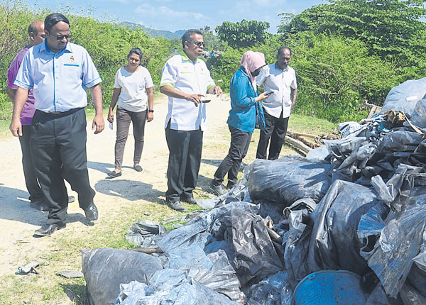 威拉班（左）指示官员收集垃圾样本，鉴定是否含有化学成分，以免河流污染破坏生态。