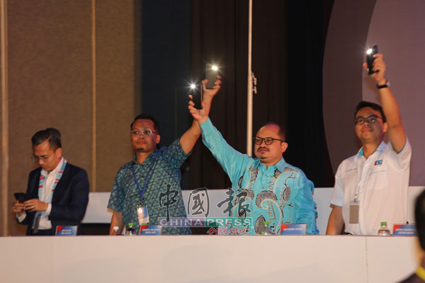 公正党通讯局主任法米（左起）、大会秘书聂纳兹米及宣传主任三苏依斯干达，在台上随歌声一起亮起手机手电筒。