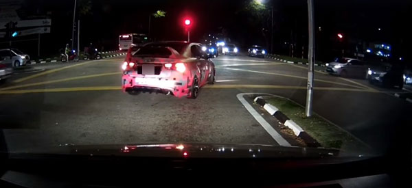 一辆装饰到非常拉风的红色轿车，不理会红灯，直接驶进十字路口。
