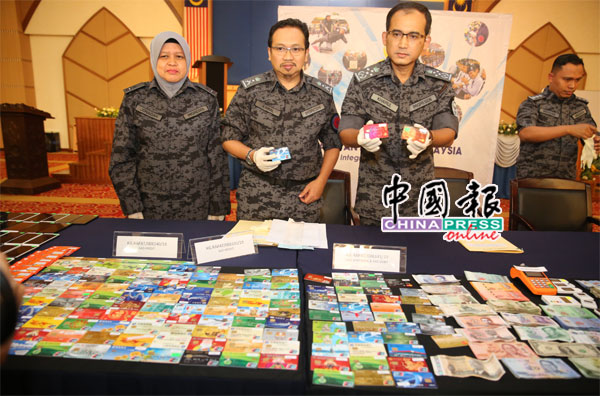 佐奈达（左起）、英德拉凯鲁、卡马鲁丁展示行动中起获的中国信用卡。