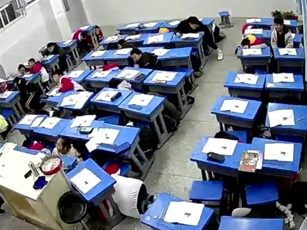 地震发生时，内江威远县凤翔中学学生赶紧躲到桌下避险。（寰宇新闻网）