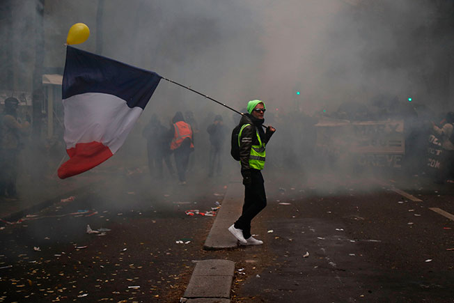黄背心示威者，肩上扛着一面法国国旗。（法新社）