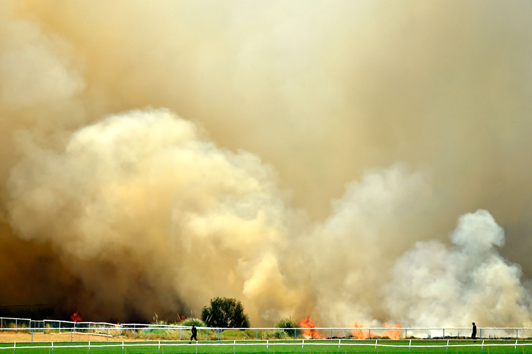 柏斯市的柏斯板球场外周五遭林火焚烧，浓烟弥漫。（法新社）