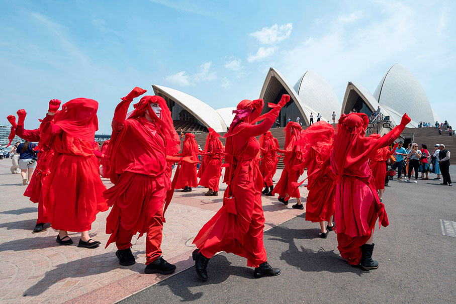 “反抗灭绝”运动的示威者一致穿着红色长袍、脸上带着全白的妆容，在歌剧院前方的广场绕行。（法新社）