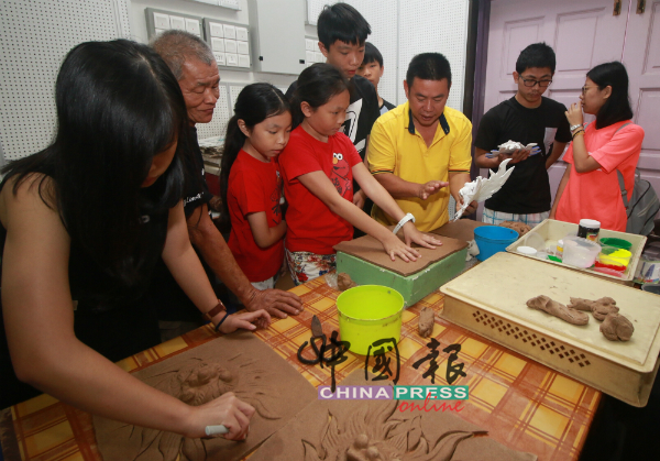 武吉不兰律百吉龙香厂东主黄聿雄（右3）现场让人们亲身体验龙香龙头的制作。