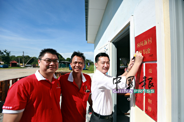 谢琪清（右）在拉杭新村图书馆外的牌匾签名。左为王祖烈，中为刘秋兴。
