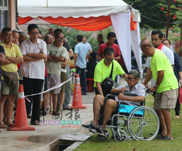 坐在轮椅的行动不便者也到来投票，在场的村民上前协助，气氛和谐。