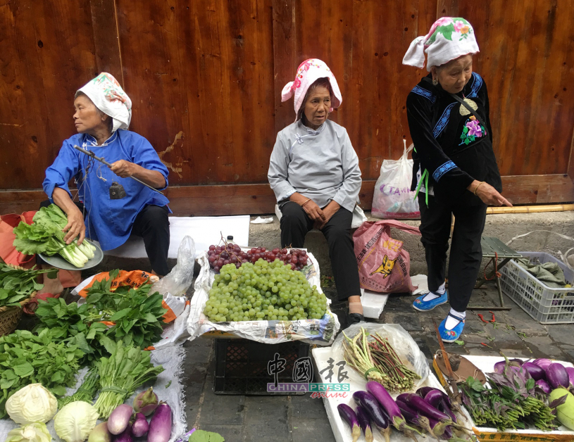 菜市场的苗族妇女，穿着苗服在卖菜。