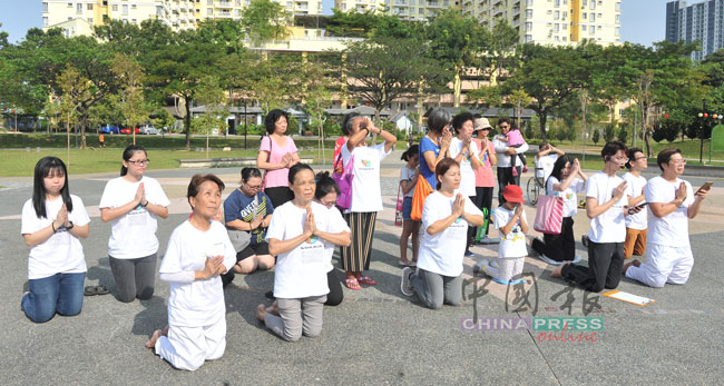 约20男女老少双手合十，跪地祈祷。