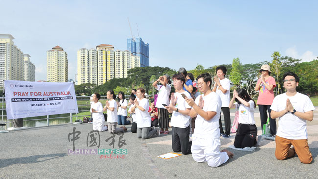 约20男女老少双手合十，跪地祈祷。