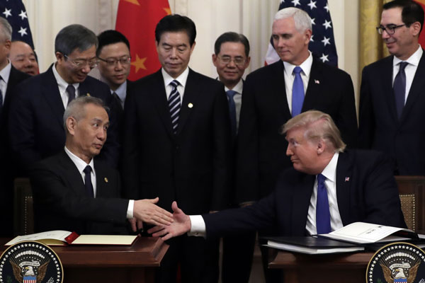 刘鹤（前左）与特朗普签署协议后相互握手。（美联社）