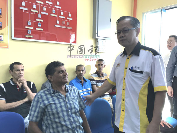 李文材（右）与与在锡米街政府诊所求诊的病人交谈及问好。