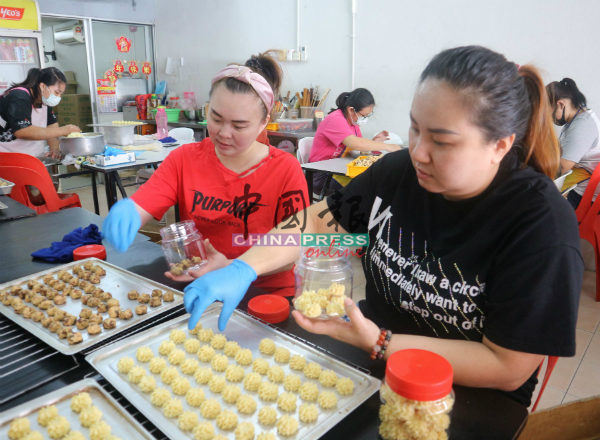 ST Ice Cafe两位负责人林丽雪（左起）与陈秋玲，把烤好的年饼装入罐子。