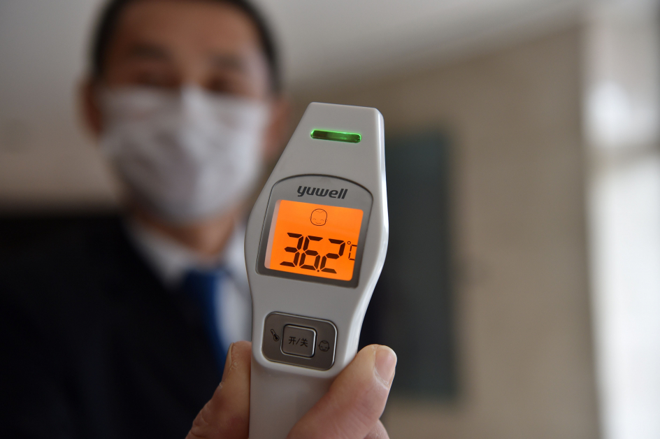 武汉肺炎的扩散程度令人担忧，中国也急速采取一连串的防疫行动，一名酒店职员为登记的房客测量体温。 （法新社）