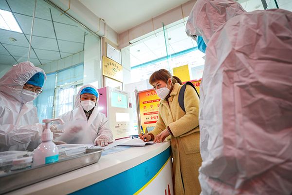在湖北省武汉市一间社区卫生所，身穿防护服、戴口罩的医疗人员与一名疑似武汉肺炎患者聊天。（美联社）