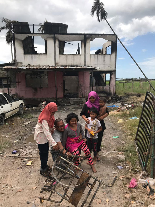 阿蒂峇（左3）与家人展示被烧毁的轮椅。