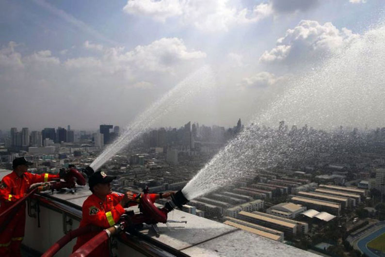 消防员在曼谷的高楼处洒水，希望能减轻空气污染，净化空气。