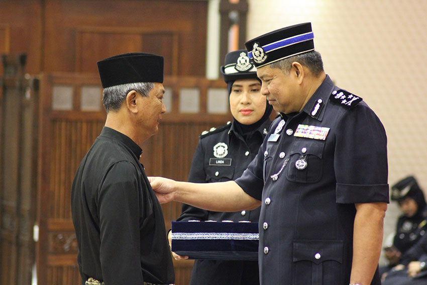 莫哈末查卡利亚（右），颁发国家英雄功勋奖章给有功警员。