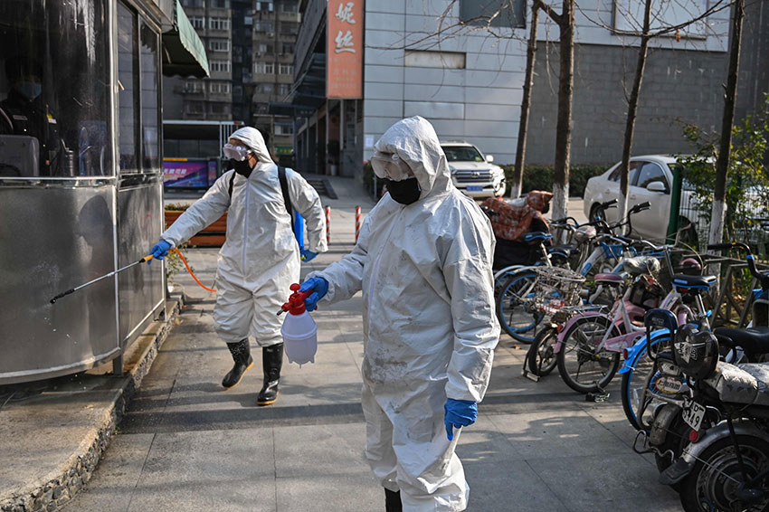 穿着隔离衣的清洁人员，周四在武汉街头进行消毒。（法新社）