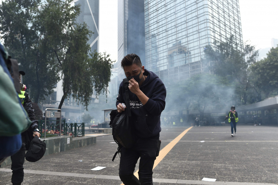 警察发射催泪弹，现场烟雾弥漫，示威者捂着鼻子离开。（法新社）