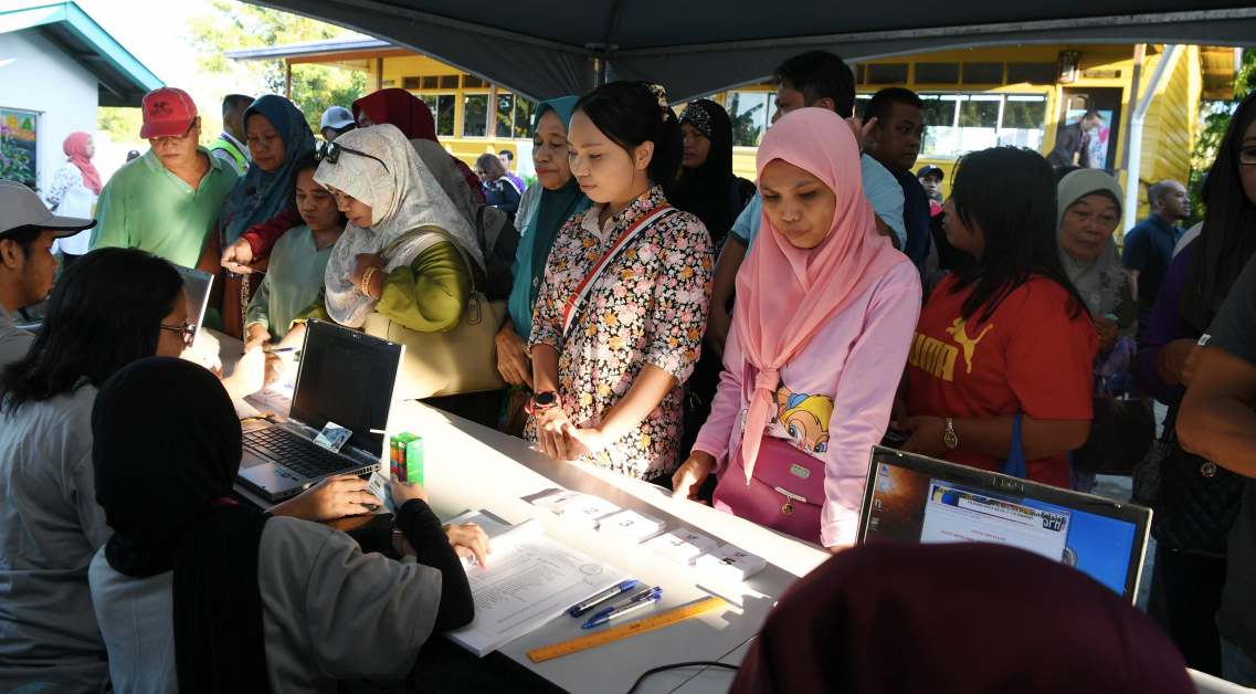 选民在金马尼士学校外列队，以检查自己所属的投票室。