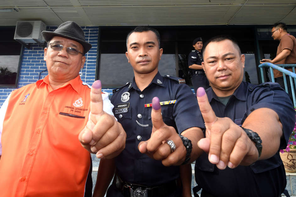 几名选民在投票完成后展示手指上的墨水印。