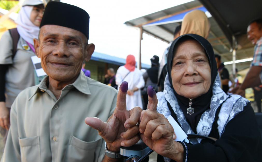 一对乐龄人士夫妇莫哈末诺沙鲁丁（左）与妻子达央拉玛达丽在金马尼士国小投票后，向媒体展示粘墨的手指。