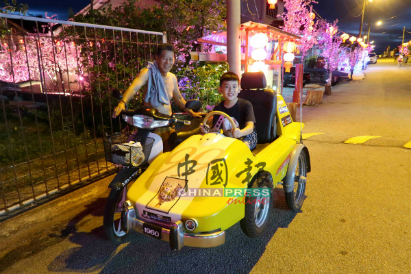 傅协隆（左）与到访梅花街的小朋友，乘坐造型独特的三轮摩哆。