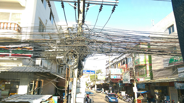 泰国国内各地随处可见电话线、电缆线将电线杆、电塔团团包围，更有电缆还会横越马路，形成泰国“另类风景”。