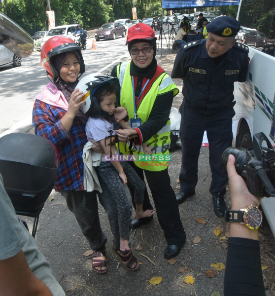 道路安全理事会人员，为孩童戴上头盔。