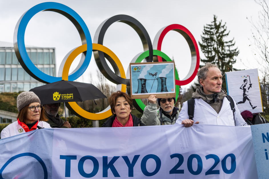民众在瑞士洛桑国际奥委会总部的五环标志旁，以核难的形式反对东京奥运会，在扩散至全球的疫情下继续举办。（欧新社）