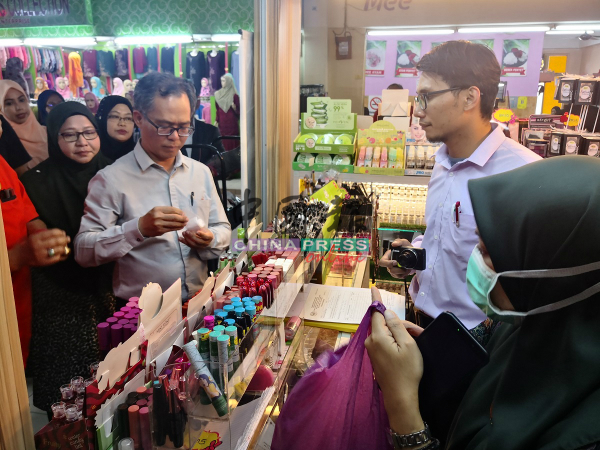 刘志良（左2）检查摊位所售卖的产品。