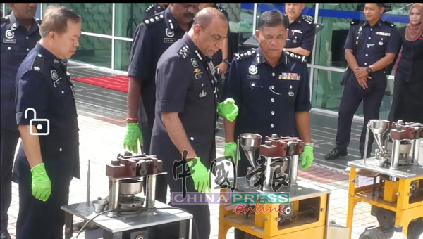 莫哈末卡里尔（中）展示新发现的制作冰毒原料，左为曼绒警区副主任钟武钦。