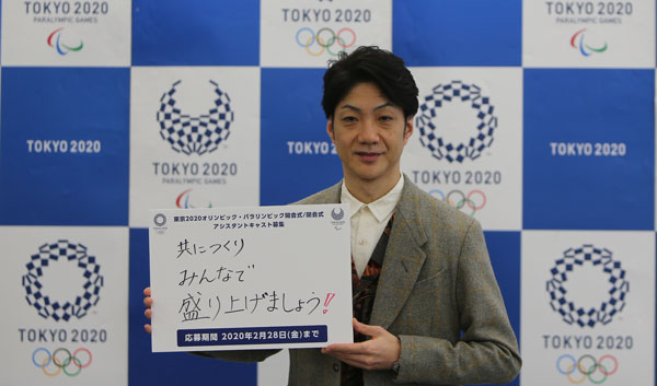 野村万斋在引导员招募活动中，展示写有“共创奥运，携手同庆”的招募牌。（新华社）