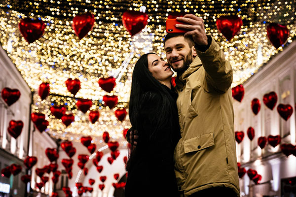 俄罗斯莫斯科一对情侣，情人节前夕在心形气球下拍照。