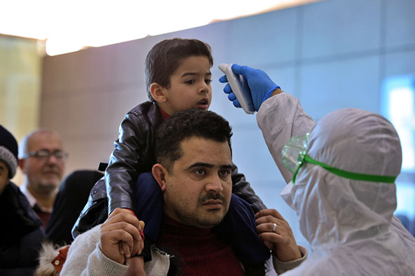 医疗人员周五在伊拉克纳杰夫机场，为来自伊朗的旅客测量体温。
