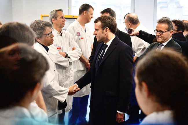 马克龙周四在巴黎一家公立医院视察医疗团队，和一名医护人员握手。（欧新社）