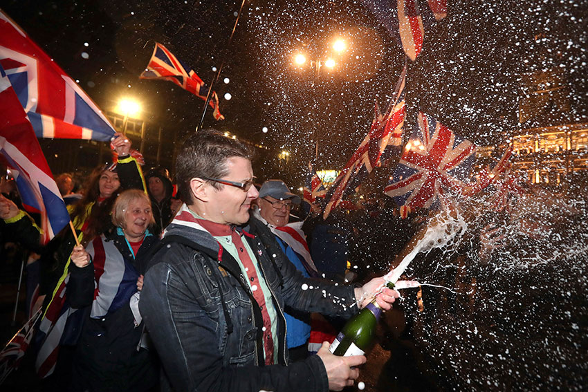 脱欧支持者在英格兰格拉斯哥的乔治广场，开香槟挥国旗庆祝。（美联社）