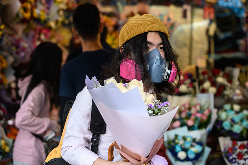 香港一名男子，戴着防护口罩购买鲜花庆祝情人节。（法新社）