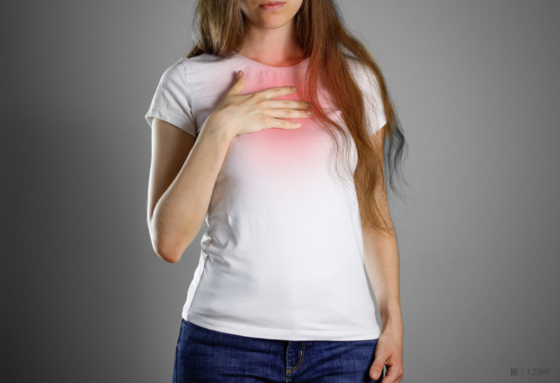 A woman holds the Breasts. The pain in her chest. Heartburn. Stomach hurts. Sore point highlighted in red. Closeup. Isolated.