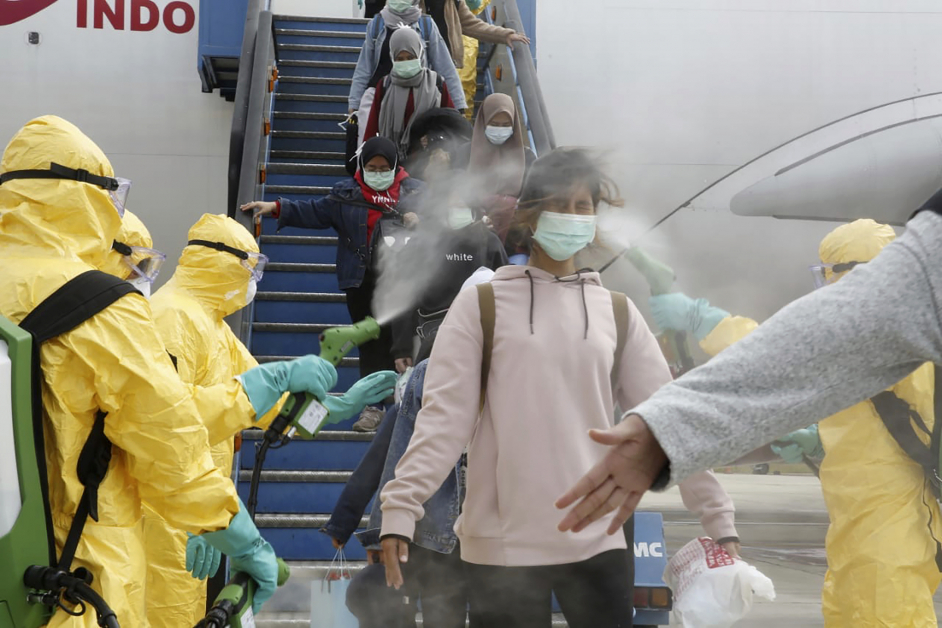周日（2日）从武汉回到印尼的印尼公民下飞机后，医护人员在他们的身上喷洒消毒水。