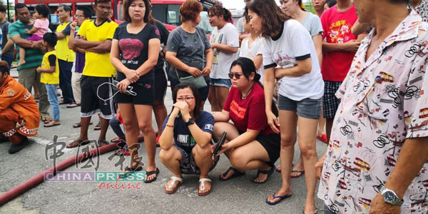 胡丽凤(蹲者左)伤心哭泣。