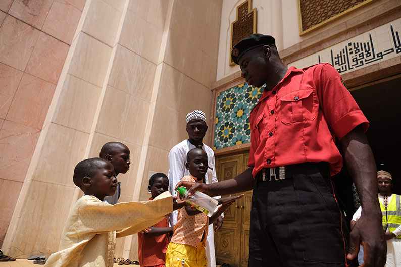 在尼日利亚的国家清真寺，保安人员为前来祈祷的信徒喷上搓手液消毒。（法新社）