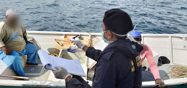 海事执法机构人员载上口罩，向漂流15小时的渔夫问话。