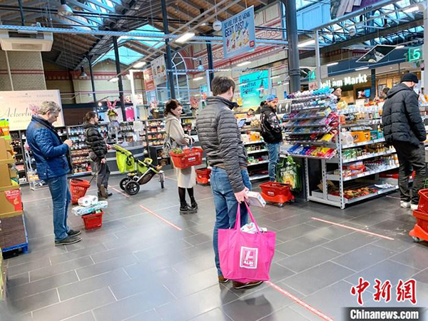 柏林一家超市等待付款的人们相互隔开了1.5公尺的距离。（中新网）