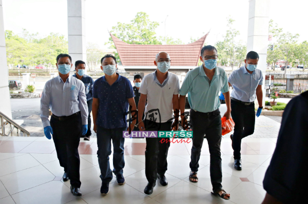  3名被告戴着口罩（前排左2起），被戴着口罩及手套的警员带上法庭面控。