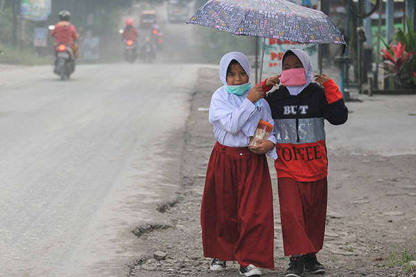 火山喷发造成空气污染，2名小学生走路去上学时戴口罩。 （欧新社）